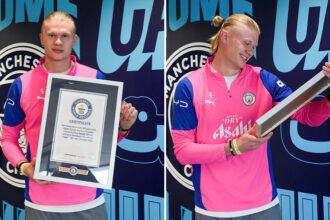Erling Haaland standing proud while holding his four official Guinness World Records certificates at Etihad Stadium
