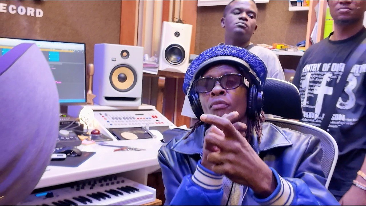 Jose Chameleone performing in front of a microphone in the studio with Jeff Kiwa.