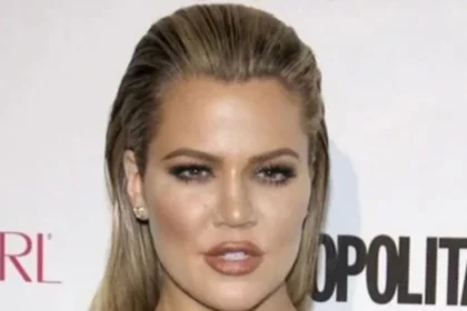 Khloé Kardashian smiling at a family event wearing a casual outfit.
