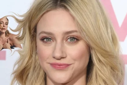 Lili Reinhart smiling on a red carpet, wearing a black dress with her hair styled in loose waves