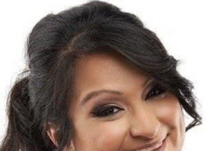 Aphmau (Jessica Bravura) sitting at a computer desk, wearing a headset, playing Minecraft on her YouTube channel.