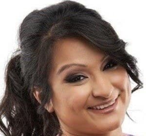 Aphmau (Jessica Bravura) sitting at a computer desk, wearing a headset, playing Minecraft on her YouTube channel.