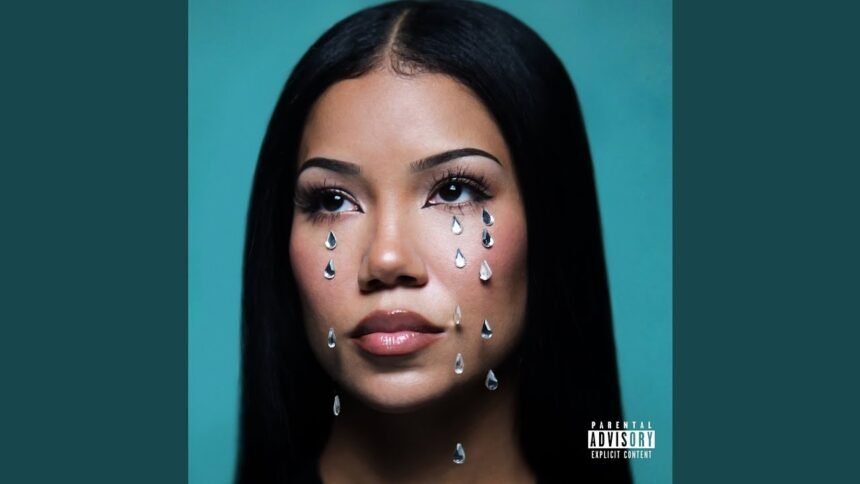 Jhené Aiko singing into a microphone on stage.