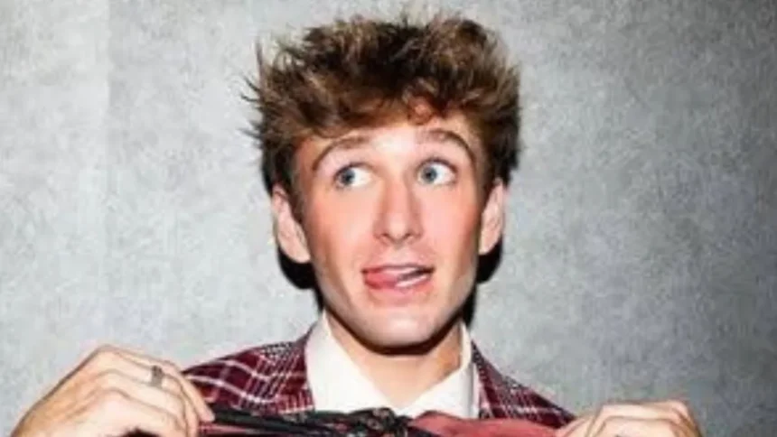 Carter Kench smiling while holding a phone, showing his TikTok video background with bright lights.