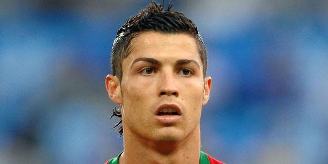 Cristiano Ronaldo in a soccer jersey raising his arms after scoring a goal, with a stadium crowd in the background.
