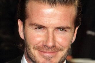 David Beckham smiling while wearing a suit at a public appearance
