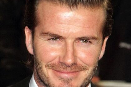 David Beckham smiling while wearing a suit at a public appearance