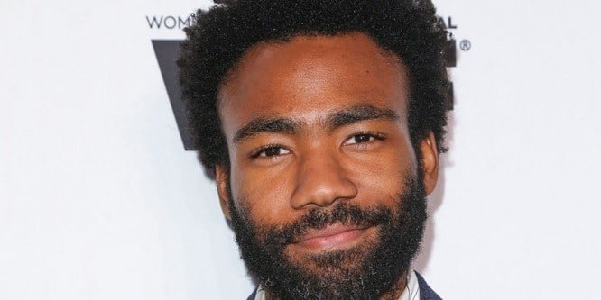 Donald Glover wearing a casual shirt, standing on a city street set while filming Atlanta.