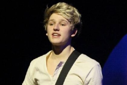 Drew Dirksen singing on stage with his band The Tide, holding a microphone, with bright stage lights behind him.