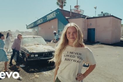Freya Skye sings in a colorful set with neon lights, wearing a bold outfit while the camera captures close‑up shots of her expressive performance in the "bad taste" music video.