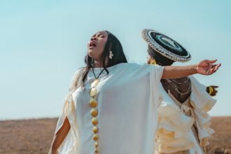 Nontokozo Mkhize and Zawadi Yamungu standing on a hill in the Drakensberg mountains, singing together for the music video of the song "Glory".
