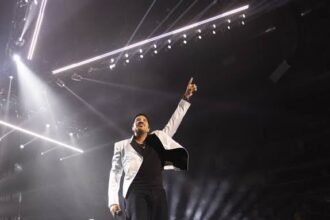 Lionel Richie singing into a microphone on stage under stage lighting
