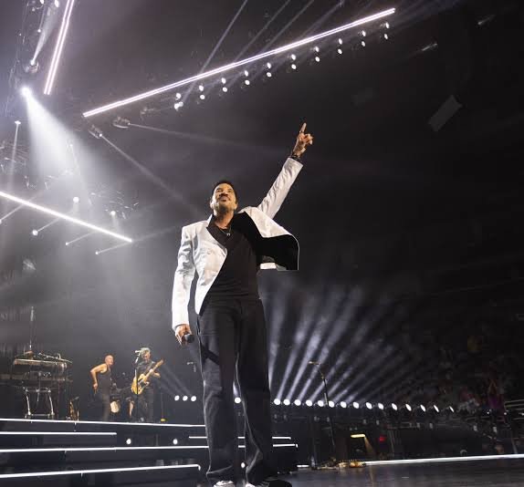 Lionel Richie singing into a microphone on stage under stage lighting