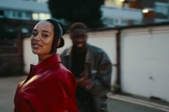 Tiakola and Jorja Smith on stage singing together, with bright lights behind them while performing Jet Lag.