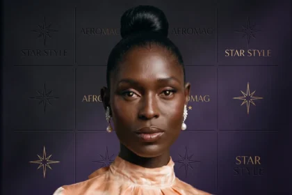 Jodie Turner-Smith wearing a black dress on a red carpet, smiling at cameras