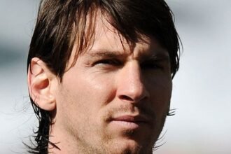 Lionel Messi wearing Inter Miami jersey, standing on the field with a soccer ball.