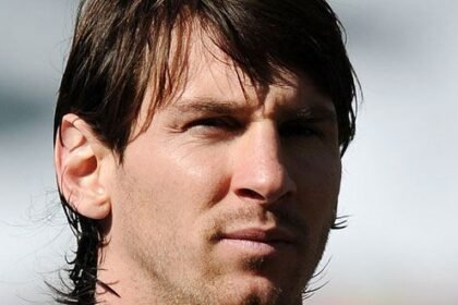 Lionel Messi wearing Inter Miami jersey, standing on the field with a soccer ball.