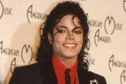 Michael Jackson in a glittering outfit performing his hit song on a large concert stage with bright lights