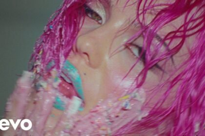 ADÉLA wearing a red corset and dramatic makeup in the 'Nicole Kidman' music video directed by Hannah Lux Davis