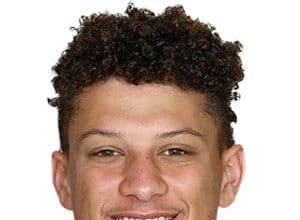Patrick Mahomes wearing a Kansas City Chiefs jersey, standing on the field with a football under his arm