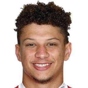 Patrick Mahomes wearing a Kansas City Chiefs jersey, standing on the field with a football under his arm