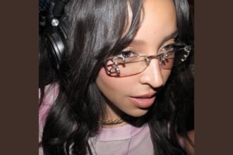 Tinashe singing into a microphone on stage during a musical performance