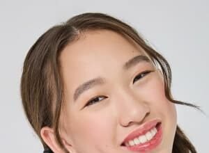 Teen actress Reagan To smiling on stage in a ballroom dance costume during a 2024 competition