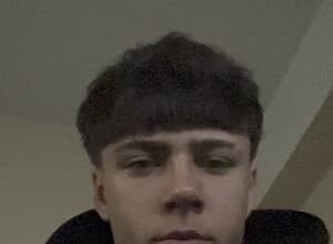 Portrait of richyidk, an 18‑year‑old TikTok creator from Talsi, Latvia, wearing a black hoodie while holding a phone.