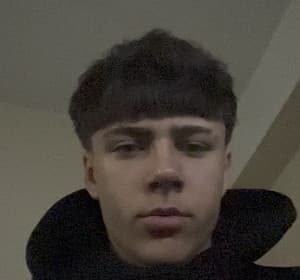 Portrait of richyidk, an 18‑year‑old TikTok creator from Talsi, Latvia, wearing a black hoodie while holding a phone.