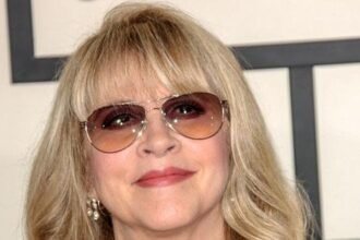 Stevie Nicks holding a tambourine while singing on stage