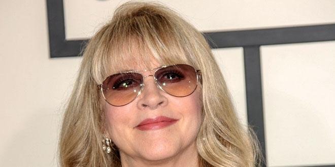 Stevie Nicks holding a tambourine while singing on stage