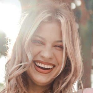 Sydney Morgan, a 24-year-old TikTok makeup artist, smiling while holding makeup brushes in a studio setting.