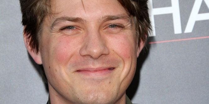 Taylor Hanson playing keyboard during a live concert, smiling and wearing a black shirt.