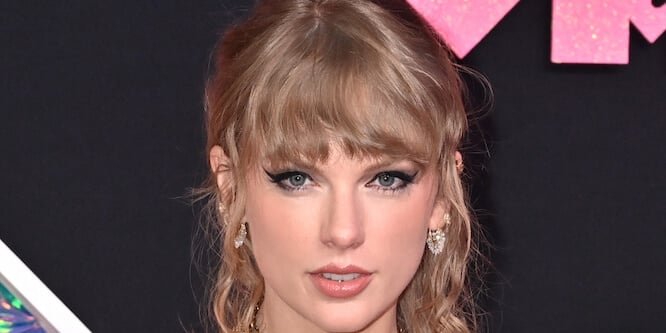 Taylor Swift smiling on a red carpet in 2025 wearing a glittering dress