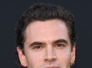 Tom Bateman smiling at a London film premiere, wearing a dark jacket and looking to the side