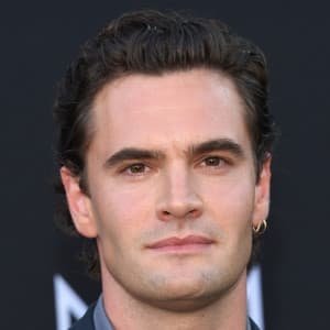 Tom Bateman smiling at a London film premiere, wearing a dark jacket and looking to the side