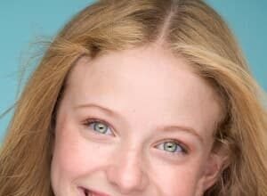 Zoe Mordas, a teenage Instagram star, smiling while holding a phone, showcasing her social media presence.