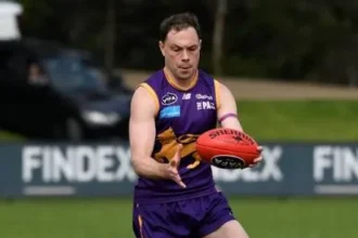 Adam Bell coaching young players on a grass field in Corio.