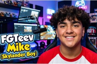 FGTeeV Mike, also called Skylander Boy, standing in front of a gaming backdrop with a bright smile.