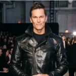 Tom Brady standing in a stadium with a smile, rumored to be dating Victoria's Secret Angel Candice Swanepoel
