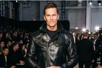 Tom Brady standing in a stadium with a smile, rumored to be dating Victoria's Secret Angel Candice Swanepoel
