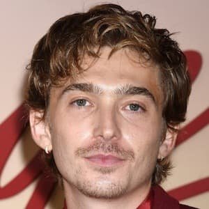 Austin Abrams smiling at a 2022 press event, wearing a black jacket.