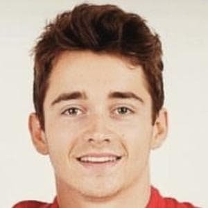 Charles Leclerc standing beside his Ferrari car at the 2024 Monaco Grand Prix with a smiling expression