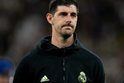 Thibaut Courtois, Real Madrid goalkeeper, shown sitting on the bench with a medical bag, indicating he missed the El Clasico match.