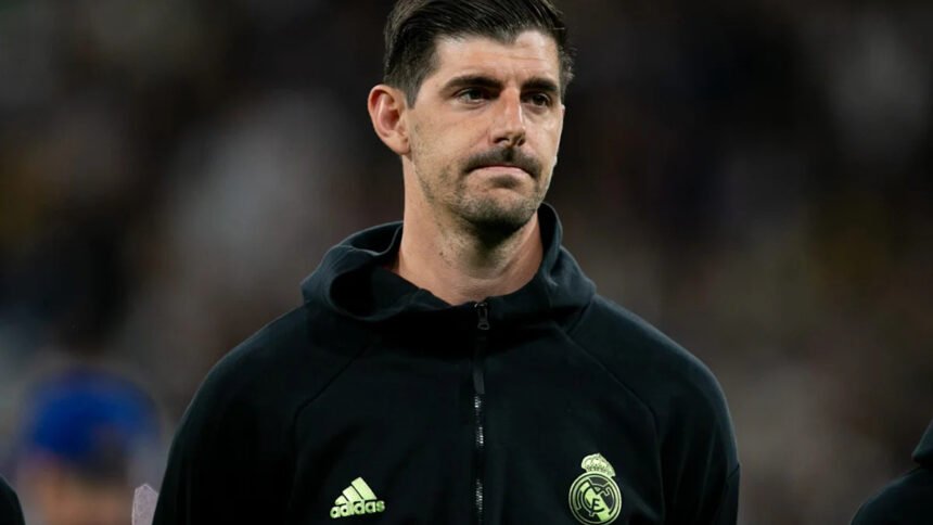 Thibaut Courtois, Real Madrid goalkeeper, shown sitting on the bench with a medical bag, indicating he missed the El Clasico match.