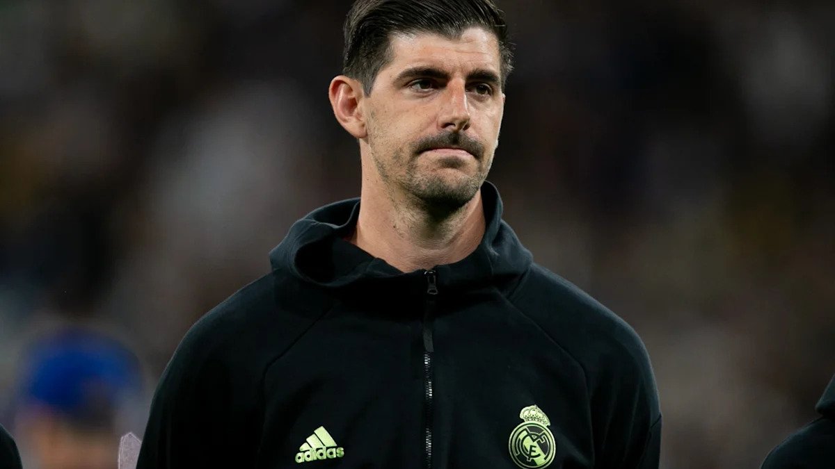 Thibaut Courtois, Real Madrid goalkeeper, shown sitting on the bench with a medical bag, indicating he missed the El Clasico match.