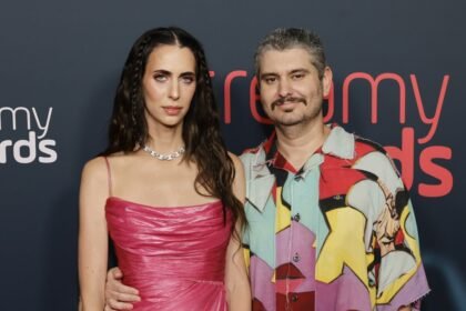 Ethan Klein and Hila Klein standing together at a media event, smiling for cameras.