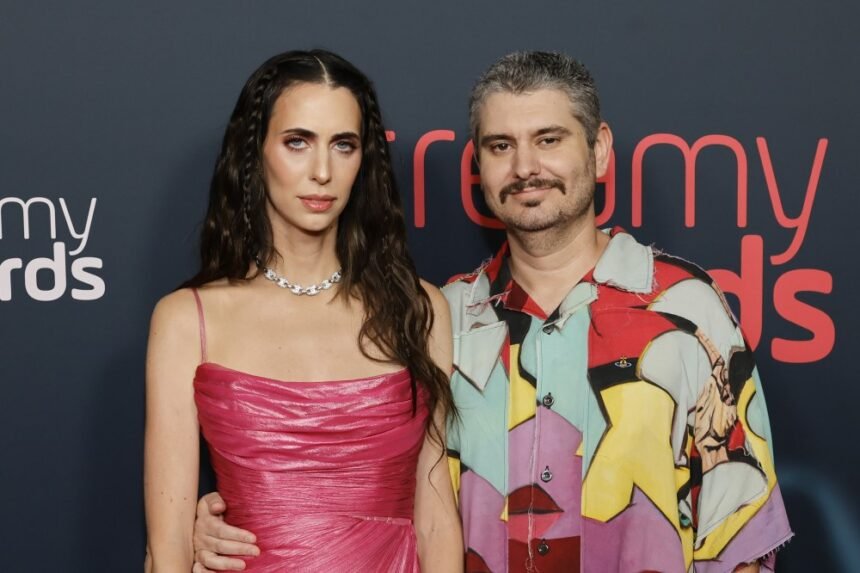 Ethan Klein and Hila Klein standing together at a media event, smiling for cameras.