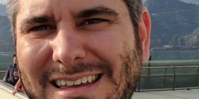 Ethan Klein, a YouTube creator, standing on stage during a public appearance, wearing a casual shirt and smiling.