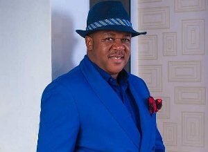 Portrait of Nigerian actor Francis Duru wearing a dark suit, smiling at a film event in Lagos.